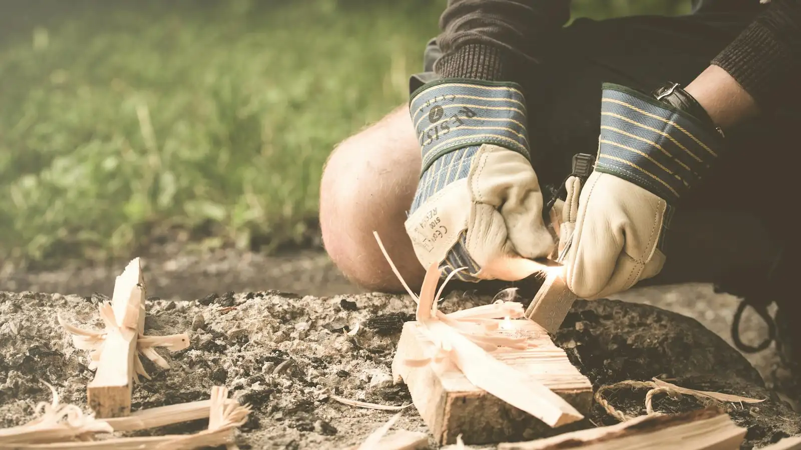 Person entzündet Holzspäne mit Feuerstahl – Symbolbild für Survival Feuer und Licht